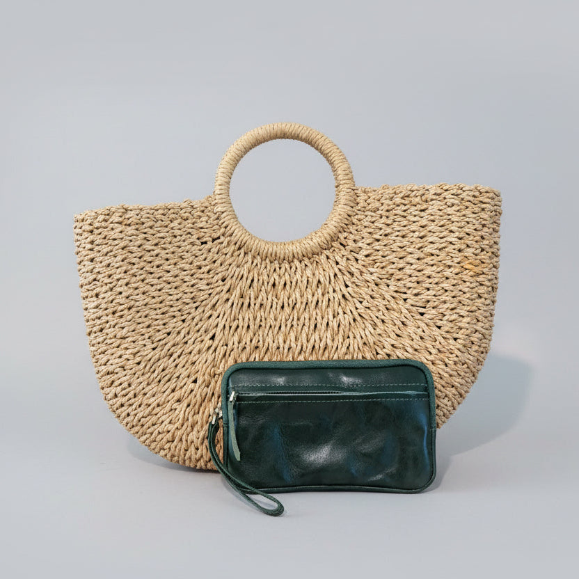 Woven straw handbag with a green clutch on a light gray background